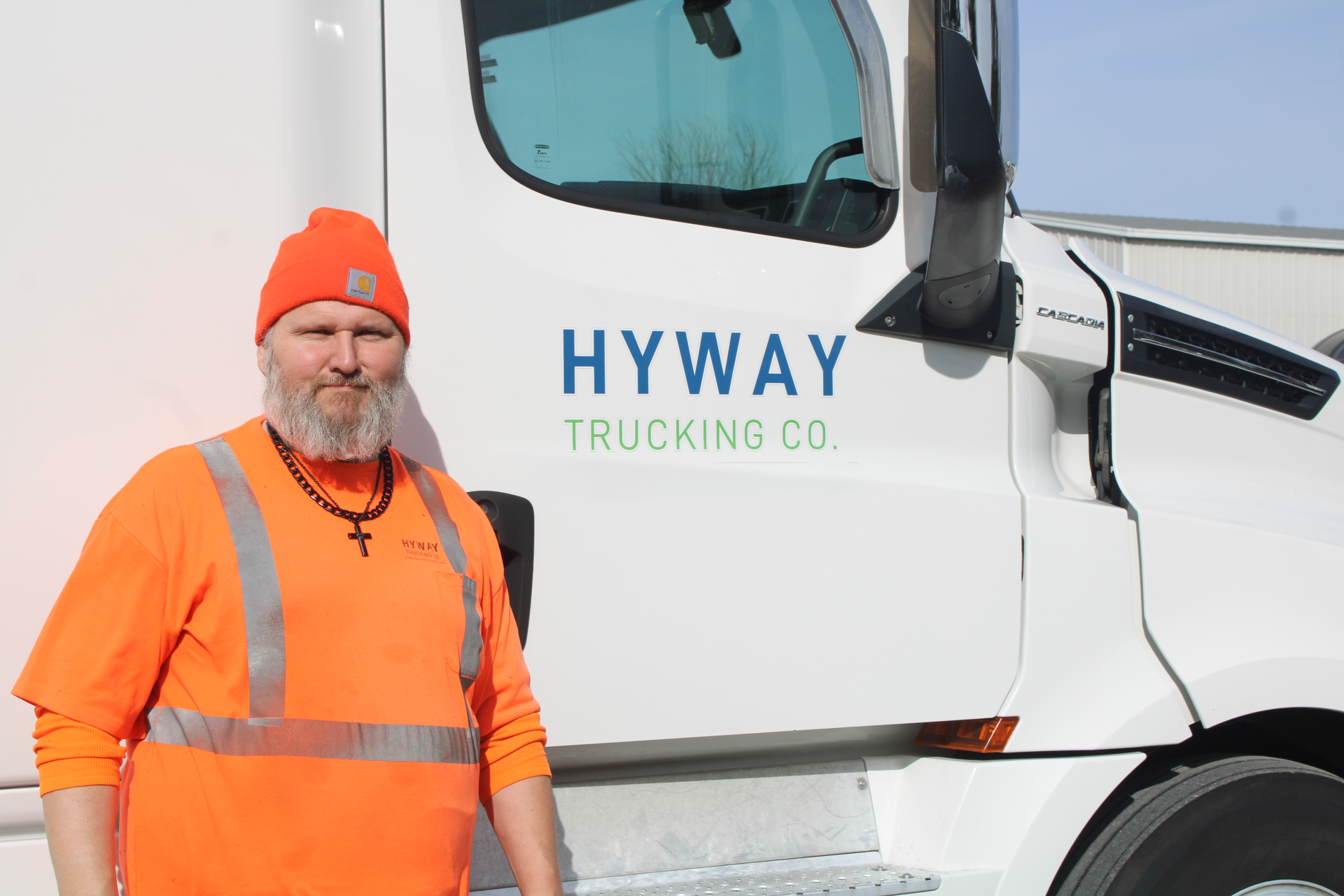 HYWAY Trucking truck driver stands in front of branded truck